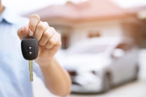 vecteezy_business-man-hand-holding-car-keys-front-with-new-car-on_17506570
